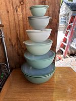 Stacked six nesting bowls of varying sizes in green and gray tones, photographed from front showing the nested bowls