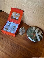 Two new crystal perfume bottles in original box with satin lining, next to heavy crystal bottle without top and porcelain dish with lid and repair tape