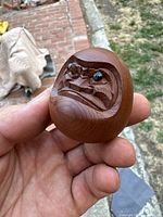 Close-up front view showing carved facial features and inset eyes of the wooden Daruma figure.