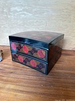 Front view of the black lacquered stacked bento box showing two visible layers with red, pink, and gold floral pattern.