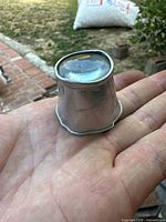 Photo of the vintage jeweler's loupe held in hand showing the glass lens with slight chip and deformities.