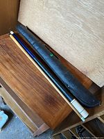 Full view of the vintage two-piece pool cue alongside its black textured zippered carrying case.