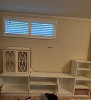 Four white book shelves arranged side by side against a wall, includes a mini glass cabinet not included in sale