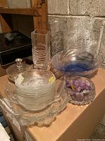 Glass items arranged on a surface including bowls, sugar bowl, and crystal bowl with amethyst stones.