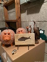 Photo showing the two red clay piggy banks, three wooden carved animals, fish fossil on sandstone, silver bird figurine, and vintage owl art in the background