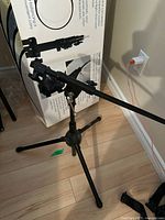 Camera light stand with boom arm extended, showing tripod legs and mounting attachments.