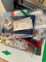 Multiple bags and envelopes filled with loose postage stamps and organized albums on a table.