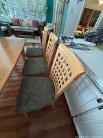 Three chairs in a row next to kitchen island showing seats and lattice backs