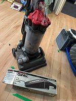 Dyson DC33 upright vacuum cleaner standing on floor with Black & Decker CarVac boxed hand vacuum in front of it.