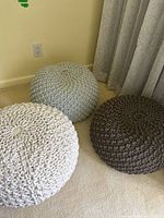 Three round seating puffs arranged on floor near curtain