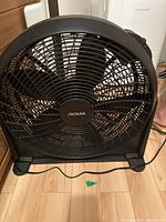 Front view of the black NOMA 20-inch floor fan showing 5 blades inside a round grille with NOMA center badge.