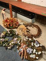 All four items: one basket filled with floral arrangement and three floral garlands laid out on the floor showing their details and different flower colors and designs.