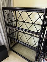 Front and angled view of the shelving unit showing the metal frame with lattice design and three glass shelves.