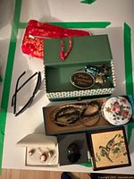 Overview of jewelry and accessories, showing cameo earrings, red pouch, jewelry boxes, and costume jewelry