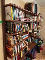 Full view of modular wall-mounted teak shelving system with books displayed