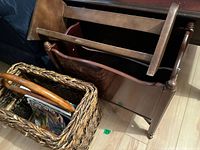 Three magazine stands, two wooden and one wicker basket, all holding various magazines.