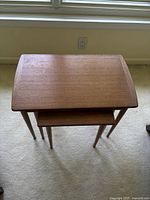 Three teak nesting tables stacked inside one another, top-down view