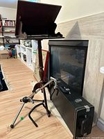 Overall view showing wooden music stand, metal tripod stand, closed sax case