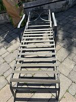 Top-down view of metal patio lounge chair frame showing slatted seat design and arm rests