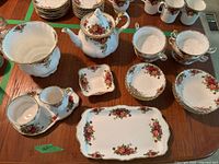 Overall layout of tea set on wood table showing bowls, teapot, trays, creamer and sugar bowl