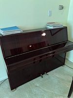 Front view of Samick upright piano showing high-gloss mahogany finish and sheet music on top