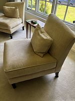 Front-left perspective of one chair with accent pillow, showing upholstery color and cushion profile.