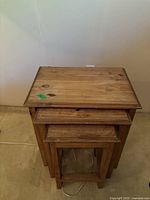Top view of the stacked wooden nesting tables showing natural wood grain and knots, highlighting the largest table's surface.