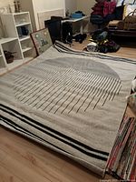 Full view of Surya Pisa area rug laid on the floor showing its modern geometric circle and horizontal stripe design in cream and black.