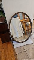 Full view of oval mirror leaning against wall