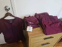 Set of magenta scrubs on hanger and folded showing quantity