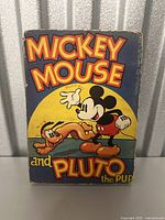 Front cover of the 1936 Mickey Mouse and Pluto the Pup hardback book showing vintage artwork and wear.