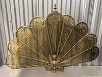 Full front view of brass fan-shaped fireplace screen against corrugated background