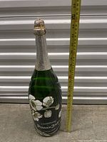 Front view of the large Perrier-Jouet champagne bottle with measuring tape showing approximately 23 inches tall.