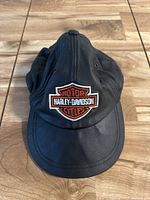 Front view of black leather Harley Davidson hat with embroidered logo on front.