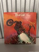 Vinyl record album cover for Meat Loaf's Bat Out of Hell showing illustrated cover art with a biker and flames. The cover has visible wear and scratches.