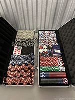 Open metal case containing organized poker chips in various colors and a deck of playing cards.