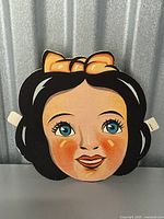 Front view of the vintage Snow White paper mask showing facial features and color printed design.