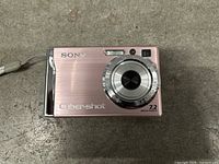 Front view of pink Sony Cyber-shot camera showing lens and branding.