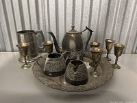 Front angle view of vintage metal kitchenware set on table against corrugated metal background