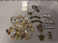 Overview of badges, pins, patches, bracelets, and earrings arranged on a table