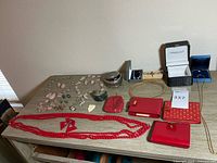 Top-down view of the assortment of vintage costume jewelry and four red wallets on a wooden surface, jewelry box visible.