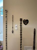 Overview of two belts, two necklaces, and wooden plaque hung on wall