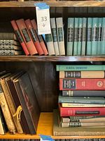 Bookshelf with various classic literature and medical books, some in sets with red, green, and blue hardcover bindings.
