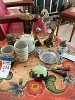 Full view of table with all items including statues, teapot with cups, lighter, utensils, and small tray on top.