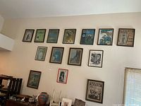 Wide view of 14 framed vintage sheet music covers hung on a wall in two rows. Frames vary in wood and black finishes. Covers show vintage artwork and distinct titles.