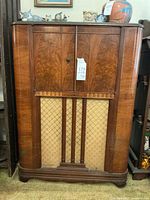 Front view of vintage wooden Stromberg Carlson radio and turntable cabinet with fabric speaker grille and wood panel door.