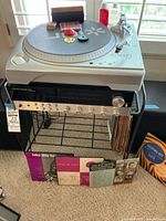 Ion TTUSB turntable on metal stand with Harman Kardon 730 receiver and vinyl records visible lower shelf