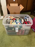 Full plastic storage bin filled with assorted holiday decorations and VHS movies.
