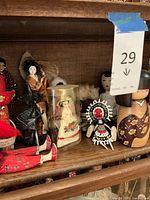 Shelf with diverse international dolls including porcelain-style doll in container, beaded doll, fabric and wooden dolls