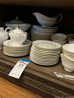 Front view of off-white china stacks: dinner, salad, bread plates, bowls, sugar bowl, creamer, gravy boat